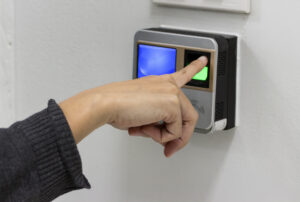Pessoa utilizando leitor biométrico com o dedo indicador em um dispositivo de controle de acesso.