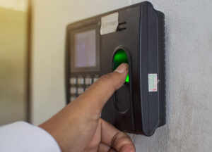 Pessoa registrando o ponto com a digital em um relógio de ponto eletrônico.