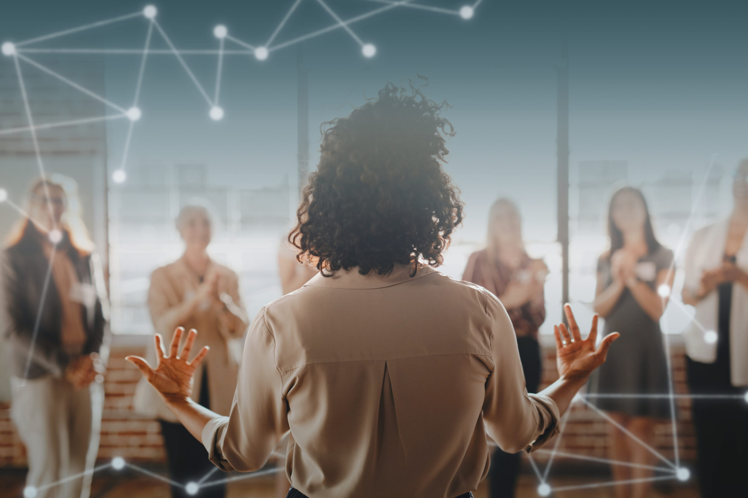 Pessoa liderando uma equipe em reunião, com profissionais ao fundo, representando liderança e engajamento.